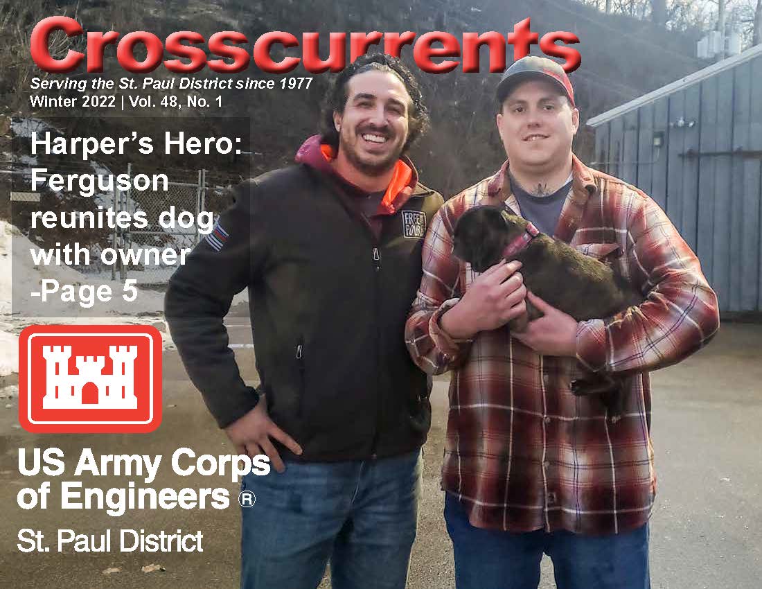 Crosscurrents Winter 2022. Two men stand next to each other, one of them is holding a dog.