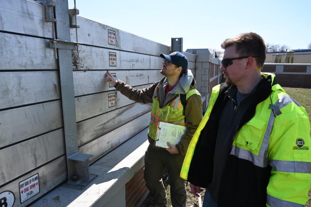 Two men examine a wall outside Two men examine a wall outside