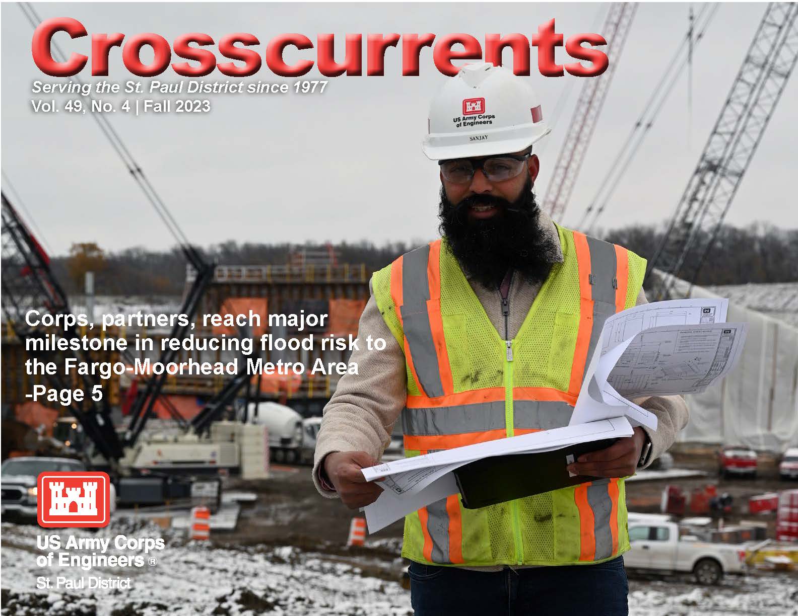 The cover of the Fall 2023 issue of Crosscurrents. There is a man in a hard hat, safety glasses and a reflective vest standing in front of a construction site. The man is looking at sheets of paper. 