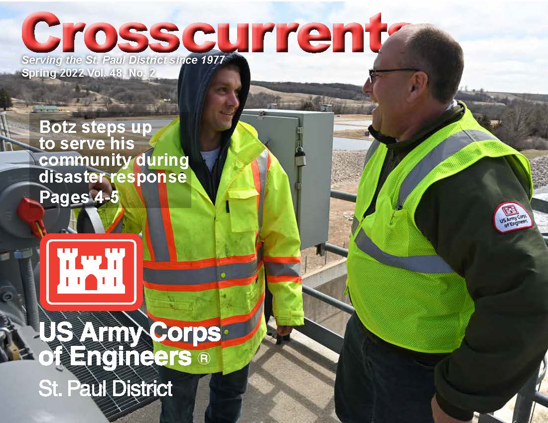 The cover of the Spring 2022 issue of Crosscurrents. Two men in high visibility vests stand outside near a body of water.